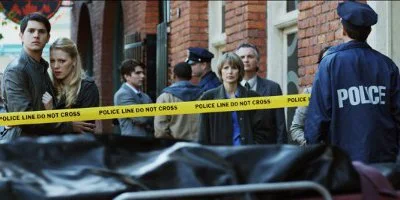 Young Couple Looking At A Body Bag From Behind Yellow Police Tape
